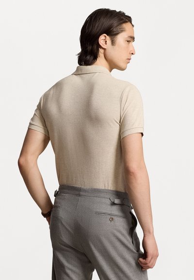 Beige polo shirts med korte ærmer, ribbet krave, kombinert med grå skreddersydde bukser med beltehempe og en baklomme med knapppynt.