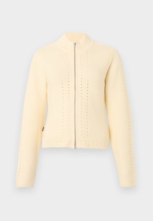 Cardigan zippé tricoté couleur crème avec manches longues, col montant côtelé et motifs perforés verticaux subtils.