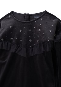Czarna aksamitna sukienka z ozdobami w kształcie srebrnych gwiazd oraz falbaną z tiulu wzdłuż talii. Zapięcie na guziki z tyłu.