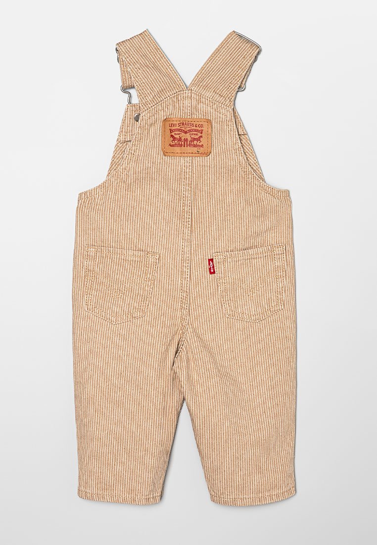 Gestreifte braune Latzhose aus strapazierfähigem Stoff. Verfügt über verstellbare Träger, eine Vordertasche und ein Rückpatch mit Logo. Zwei Gesäßtaschen.