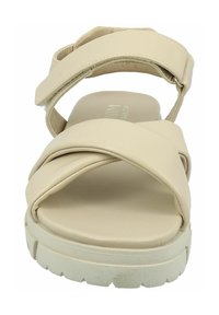Beige sandal with cross-strap design and adjustable ankle strap. Thick, white rubber sole and soft, smooth synthetic material.