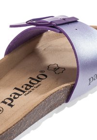 Sandalo scivoloso in pelle viola con un cinturino curvo e una fibbia. Sottopiede in sughero con una texture marrone liscia, con il nome del marchio stampato all'interno.