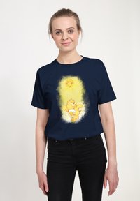 T-shirt di cotone navy con una grafica di un sole giallo sorridente e un orso con un motivo solare, centrato su uno sfondo giallo chiaro.