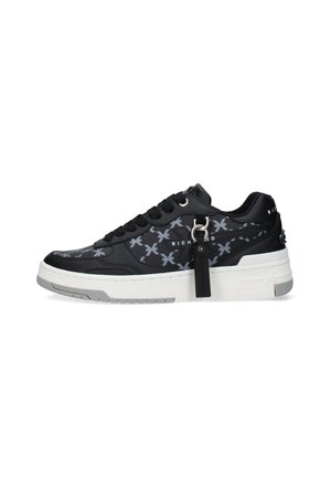 Sneaker nera low-top con marchio grigio decorato, suola bianca, lacci neri e un'etichetta nera appesa a un anello metallico sul lato.