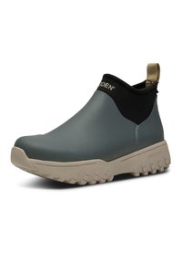 Botte à cheville imperméable avec une tige en teal mat, un col extensible noir et une semelle chunky beige dotée de profondes rainures pour une meilleure adhérence.