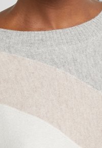 Maglione lavorato a maglia con scollo ampio, caratterizzato da strisce orizzontali in grigio soffice, beige chiaro e bianco. Tessuto leggero e con trama.