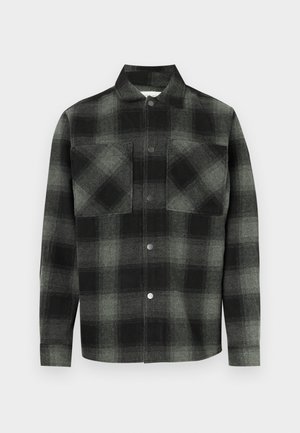 Ruuduline särk musta ja halli toonides, millel on ees nööbitav sulg, kaks rinnataskut ja krae. Valmistatud tekstuurse kangaga.