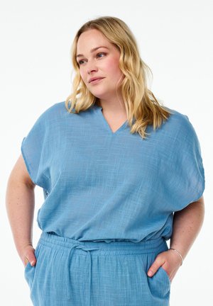 Light blue, loose-fitting top with a V-neck and short sleeves. Textured fabric with a subtle pattern, paired with an elastic waistband.