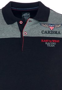 Navy und graues Polohemd aus Baumwolle. Verfügt über einen Kragen, ein gesticktes Logo mit Flügeln und rote Akzente bei der Naht und den Buchstaben.