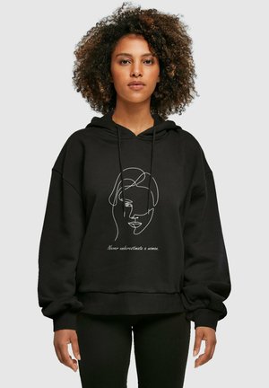 Sort oversized hættejakke med et frontprint af et kvindeligt ansigt og tekst. Lavet af et blødt materiale med en hyggelig, struktureret finish.