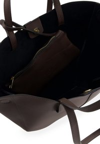 Brown leather tote bag with a black suede interior, featuring a zippered pocket, minimal hardware, and sturdy handles for carrying.
