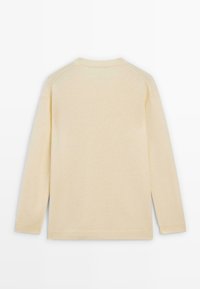 Pull beige, en matière tricotée douce, manches longues, encolure ras du cou, bords-côtes aux poignets et à l'ourlet, avec coutures raglan aux épaules, design minimaliste.