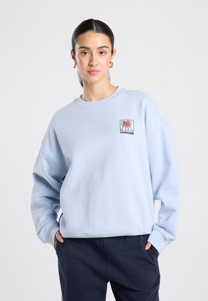 Hellblaues Sweatshirt mit lockerem Schnitt, Rundhalsausschnitt und gerippten Bündchen. Mit kleinem quadratischem Grafikdetail auf der Brust.