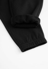 Czarne dresy z miękkim, mankietowym wykończeniem i elastycznym pasem. Materiał jest gładki z delikatnym naciągiem, zaprojektowany z myślą o komforcie.