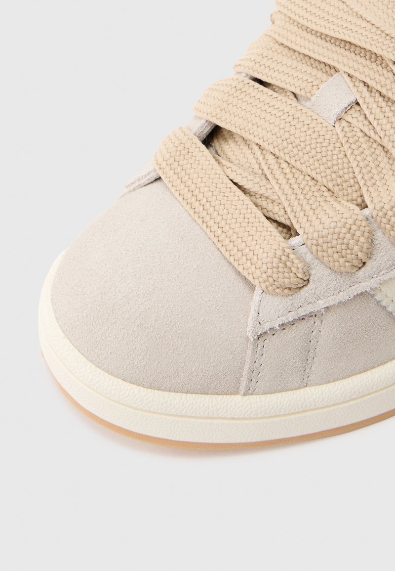 Sneaker beige in suede con tomaia strutturata, lacci spessi intrecciati e suola in gomma con accento marrone chiaro.