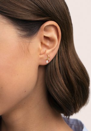 Pendientes de oro con un diseño de luna creciente, que incluyen una pequeña piedra preciosa en forma de pera y un acento adicional en forma de estrella.