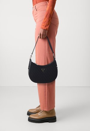 Námořnická tkaná kabelka s zaobleným tvarem a logem na přední straně. Spárovaná se světle růžovými kalhotami s vysokým pasem a hnědými šněrovacími botami.