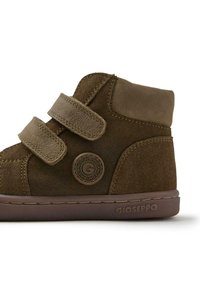 Zapatos altos de ante marrón con dos correas de Velcro, un logo circular y una suela de goma texturizada, que cuentan con un cuello acolchado para mayor comodidad.