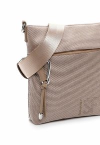 Texturovaná béžová kabelka přes rameno s tkaným designem, nastavitelným popruhem a stříbrnými kovovými detaily. Obsahuje přední kapsu na zip.