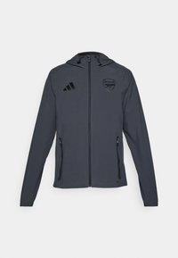 Grå hettegenser med svarte detaljer, med glidelås foran, to sidelommer og Arsenal-logo på venstre bryst. Lett materiale.