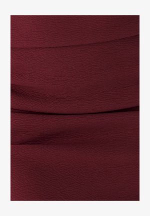 Tessuto borgogna con una leggera trama a onde, che presenta un materiale morbido ed elasticizzato che cade senza sforzo.