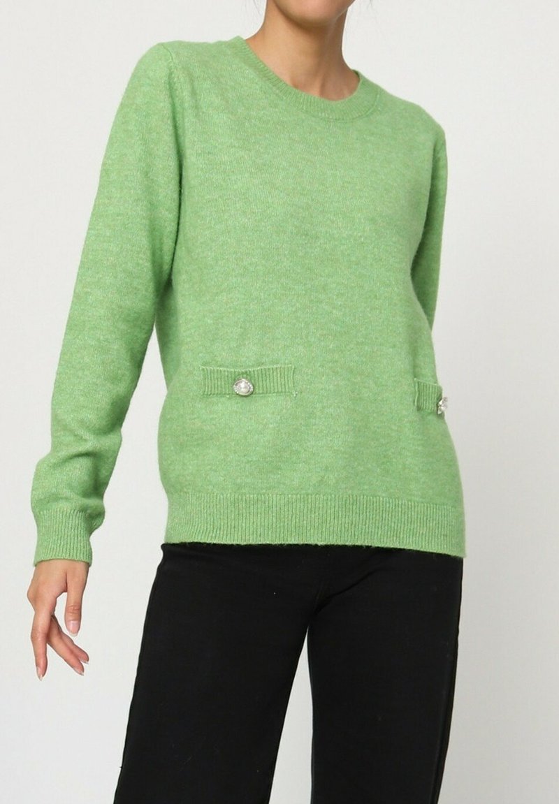 Pull en tricot vert avec des manches longues, col rond, tissu texturé et deux poches à boutons à l'avant.