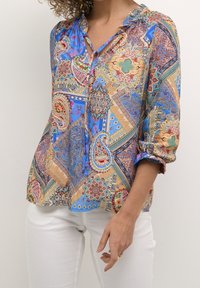 Camicia stampata colorata con chiusura a bottoni sul davanti, tessuto leggero, motivi paisley e geometrici, e maniche arrotolate.