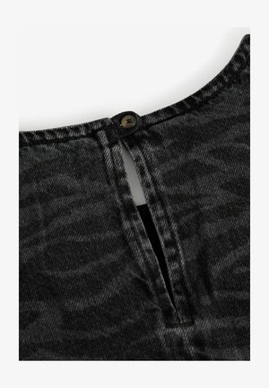 Black denim top featuring a back button closure, a small slit, and a slightly textured surface. The fabric has a muted, distressed look.