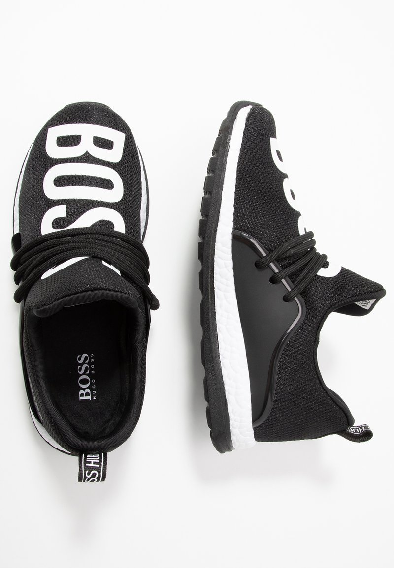 Zapatillas BOSS de color negro y blanco con parte superior de tejido, suelas interiores gruesas blancas, suelas exteriores negras y cordones negros, mostradas desde vistas superior y lateral.
