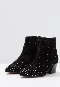 Schwarze Wildleder- ankle boots mit spitzer Zehe, ausgestattet mit einem dekorativen Muster aus kleinen silbernen Nieten und einem niedrigen, gestapelten Absatz.