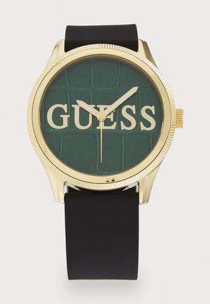 Ceas aurit cu cadran rotund texturat verde și logo-ul 'GUESS'. Curea din silicon negru, design minimalist și ace de aur pentru ore și minute.