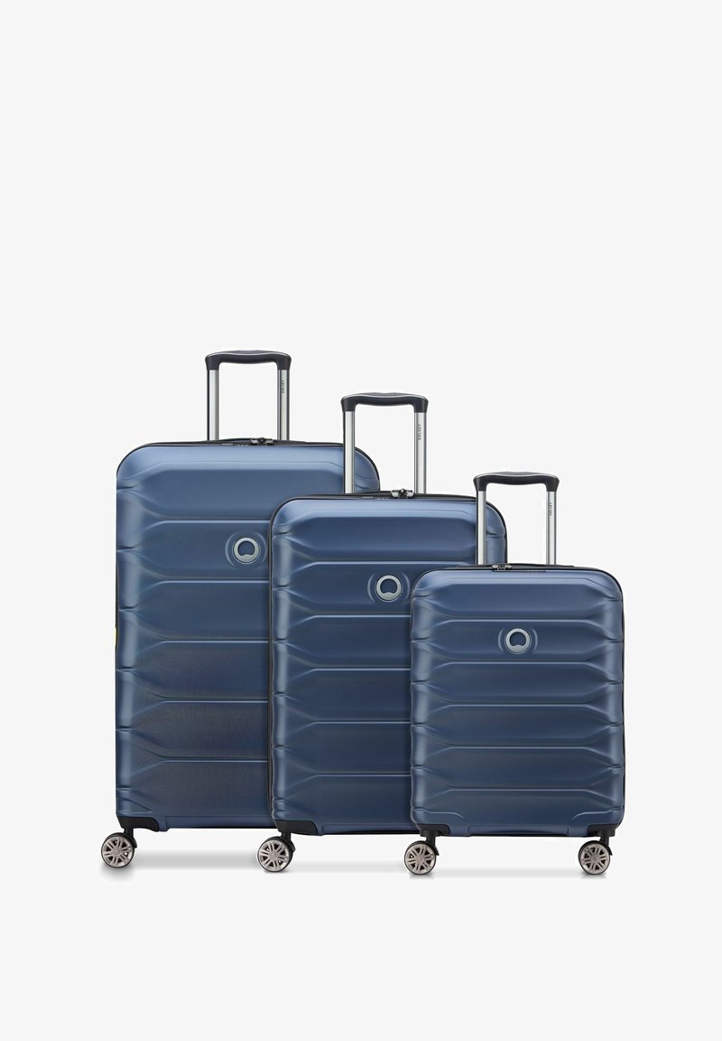 Tre valigie rigide di colore blu navy con un design a righe, manici telescopici in metallo e quattro ruote girevoli per una mobilità facile.