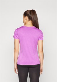 Camiseta ajustada de manga corta en color púrpura claro, hecha de una tela suave, con un escote redondo y una textura lisa. Leggings negros visibles.