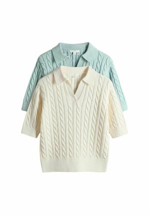 Zwei kurzärmelige Pullover mit Zopfmuster und Kragen, einer cremefarben und einer hellblau, übereinandergelegt mit dem cremefarbenen Pullover vorne.