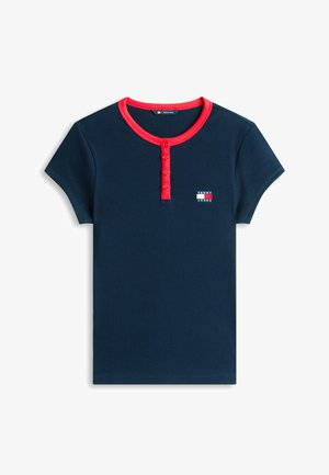 Camisa de manga corta azul marino con ribetes y botones rojos en el cuello, que presenta un pequeño logo de Tommy Jeans en el pecho.