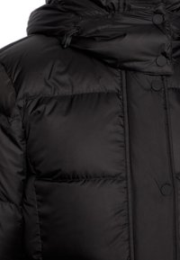 Zwarte pufferjack met een gewatteerd ontwerp, een gladde afwerking, drukknoopsluiting en een verstelbare capuchon voor extra isolatie en pasvorm.