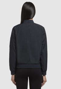 Giacca bomber di colore blu scuro con chiusura a zip, polsini e orlo a costine. Tessuto morbido e leggero con un design semplice e classico.