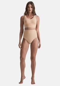 Set di reggiseno sportivo nudo e slip a vita alta, realizzato in tessuto morbido con un design aderente, caratterizzato da un sottile accento in vita.