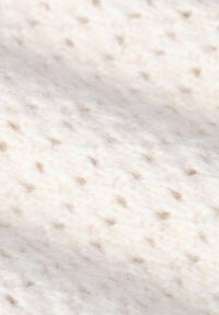 Cremefarbener Stoff mit einer weichen, strukturierten Oberfläche, die ein dezentes, gesprenkeltes Muster in hellbraunen Tönen aufweist.