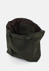 Sac fourre-tout vert foncé avec poignées noires, fermeture éclair ouverte, poche zippée intérieure et logo "HVISK" à l'intérieur et sur l'extérieur près de la fermeture éclair.