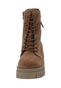Botas de tobillo de ante marrón con empuntes de cordones en la parte delantera, cremallera lateral y una suela gruesa y texturizada en tono beige. Diseño simple y funcional sin adornos.