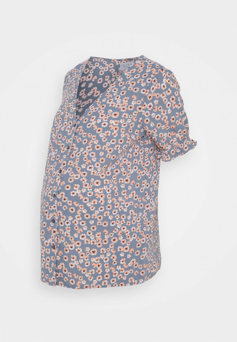 Blouse de maternité bleue à manches courtes avec petit motif floral rose et blanc et col en V sur fond blanc.