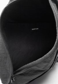 Black fabric bag interior featuring a smooth texture, zip closure, and a label reading "YOURTURN" stitched inside.