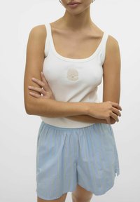 Witte geribbelde tanktop met een schelp borduursel, gecombineerd met lichtblauwe gestreepte shorts. Elastische tailleband op de shorts, relaxte pasvorm.