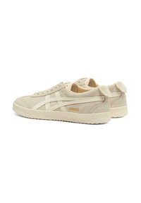 Beige Wildledersneaker mit einer strukturierten Gummisohle, weißen Lederstreifen und einem kleinen orangen "Mexico"-Detail an der Seite.