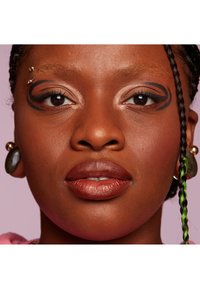 Gros plan sur un visage à la peau foncée, avec un design d'eye-liner noir audacieux, des cheveux tressés aux accents verts et de grandes boucles d'oreilles. Texture lisse et uniforme.