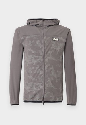 Halli lukuga kapuutsiga dressipluus peene kamuflaažimustriga, valmistatud siledast kangast, millel on reguleeritav kapuuts ja elastsed varrukaotsad. Hemmil mustad detailid.