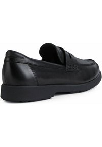 Mocassino in pelle nera con profilo basso, tomaia morbida, dettagli cuciti e suola in gomma testurizzata. Nessun hardware o accento visibile.