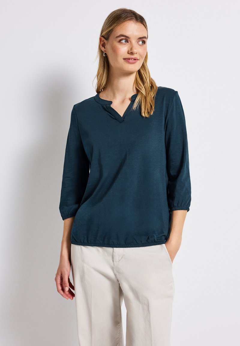 Türkisfarbener Pullover mit V-Ausschnitt, Dreiviertelärmel und elastischen Bündchen. Glatte Textur, lässige Passform und gerafftes Saumdetail.