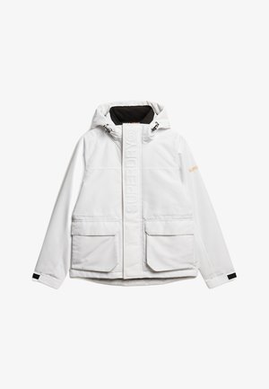 Chaqueta blanca impermeable con capucha, tela texturizada, bolsillos frontales, logo prominente en la parte delantera y forro negro contrastante.